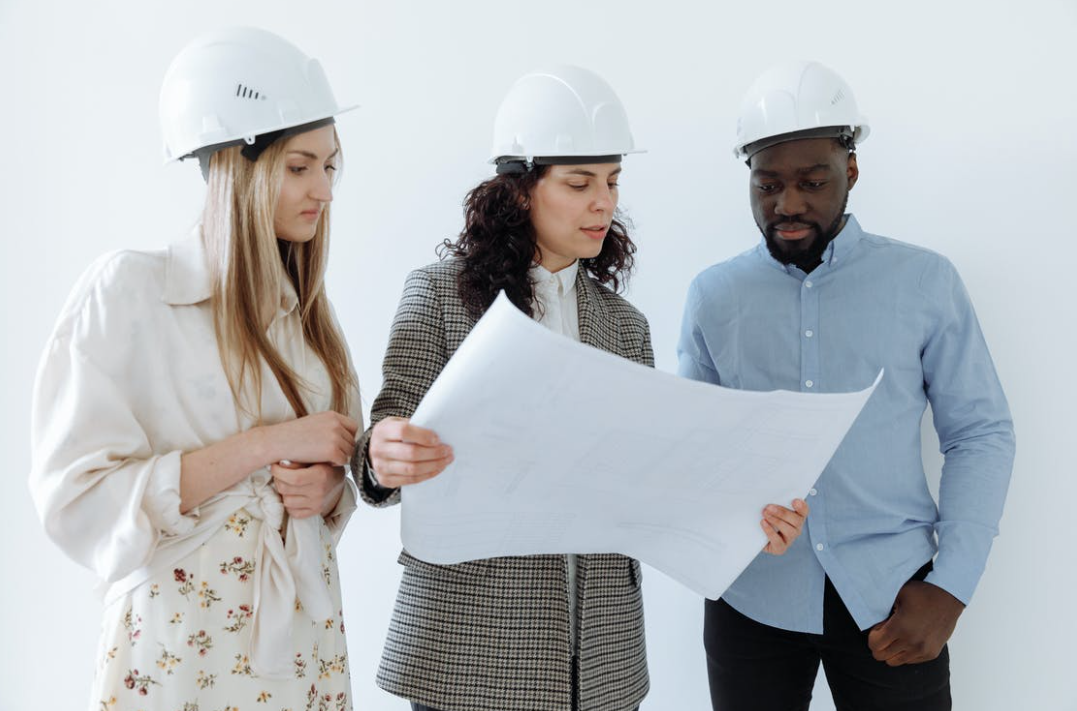 people wearing white hard hats looking at sheet of paper